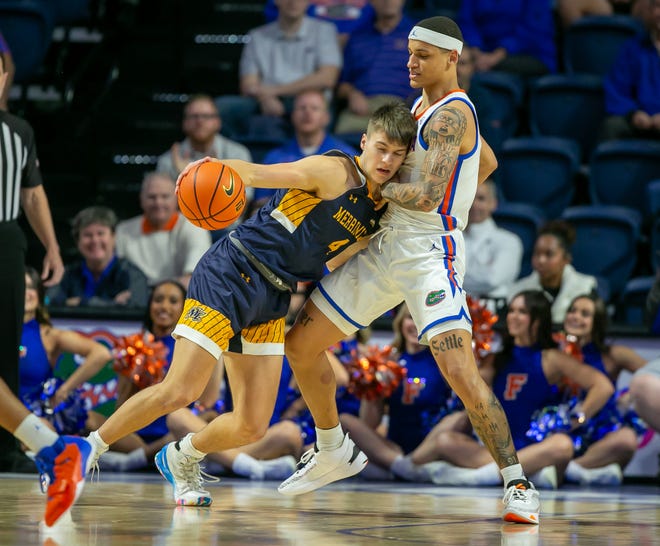 Merrimack College Jordan Derkack (4) drives against Florida Gators guard Riley Kugel (2) during first half action of an NCAA basketball game as Florida Gators take on Merrimack College Warrors at Exactech Areana in Gainesville, FL on Tuesday, December 5, 2023. [Alan Youngblood/Gainesville Sun]