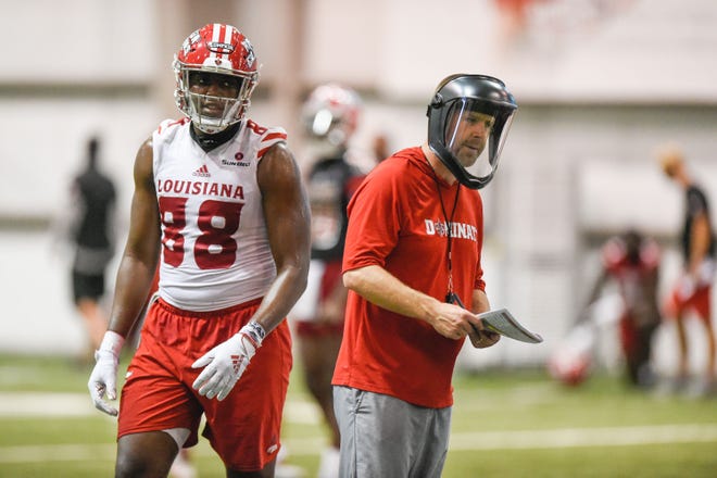 UL coach Billy  Napier, shown here alongside tight end Johnny Lumpkin, was wearing a face shield to guard against the coronavirus (COVID-19) when preseason camp opened Friday.