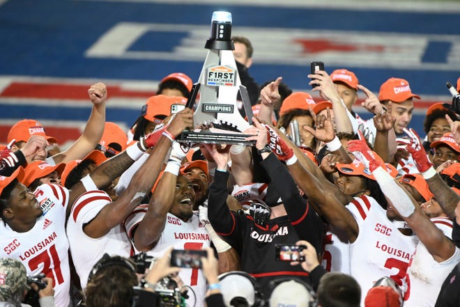 Louisiana-Lafayette linebacker Ferrod Gardner (7), coach Billy Napier and others hold up the trophy after a 31-24 win over UTSA in the First Responder Bowl NCAA college football game in Dallas, Saturday, Dec. 26, 2020. (AP Photo/Matt Strasen)