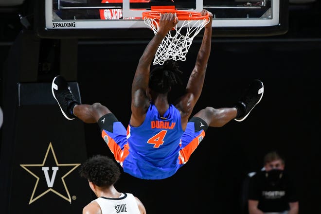 Florida forward Anthony Duruji hangs from the rim after a dunk during the first half of the team's NCAA college basketball game against Vanderbilt, Wednesday, Dec. 30, 2020, in Nashville, Tenn. (AP Photo/John Amis)