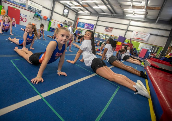 Breezy Yonkers, 9, stretches out with team member Leanne Wong and the rest of the team as the University of Florida gymnastics team put on a gymnastics clinic at Balance 180 gymnastics Gainesville, FL on Saturday, March 25, 2023. More than 100 young gymnasts learned gymnastics training and routines. They also  met the gymnasts to get autographs and pictures at the NIL Gatorverse event. [Alan Youngblood/Gainesville Sun]