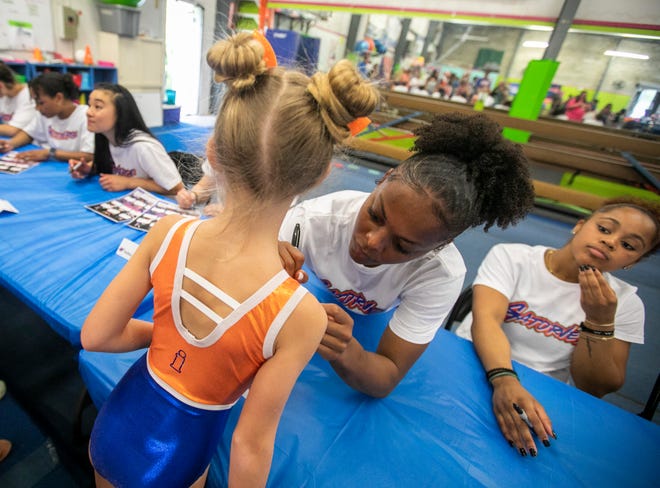 Team member Trinity Thomas signs the suit of Marcy Krautstrunk, 7, as the University of Florida gymnastics team put on a gymnastics clinic at Balance 180 gymnastics Gainesville, FL on Saturday, March 25, 2023. More than 100 young gymnasts learned gymnastics training and routines. They also  met the gymnasts to get autographs and pictures at the NIL Gatorverse event. [Alan Youngblood/Gainesville Sun]