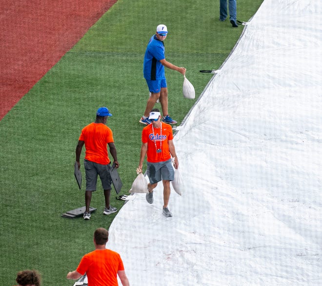 The grounds crew for the Gators pulls the tarp over the field  before the start of Game 2 of NCAA Super Regionals between Florida and South Carolina due to expected bad weather, Saturday, June 10, 2023, at Condron Family Ballpark in Gainesville, Florida. [Cyndi Chambers/ Gainesville Sun] 2023